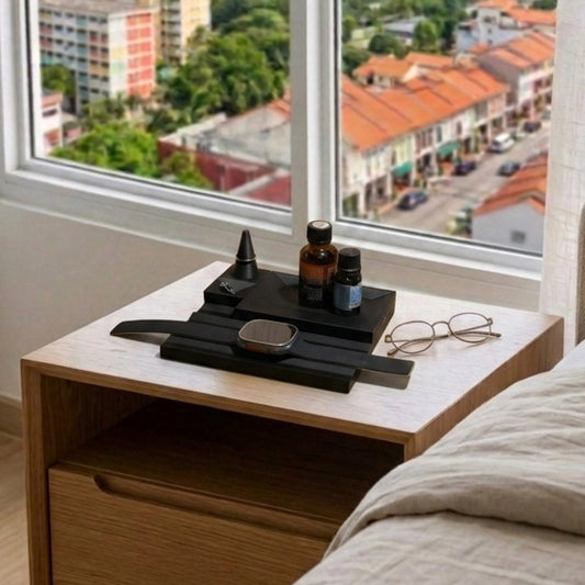 Wooden nightstand with a watch and glasses next to a window with a cityscape view.