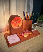 Desk organizer with lamp, stationery items, and photo on a wooden surface.