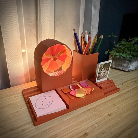 Desk organizer with lamp, stationery items, and photo on a wooden surface.