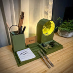 Green desk organizer with various items on a wooden surface